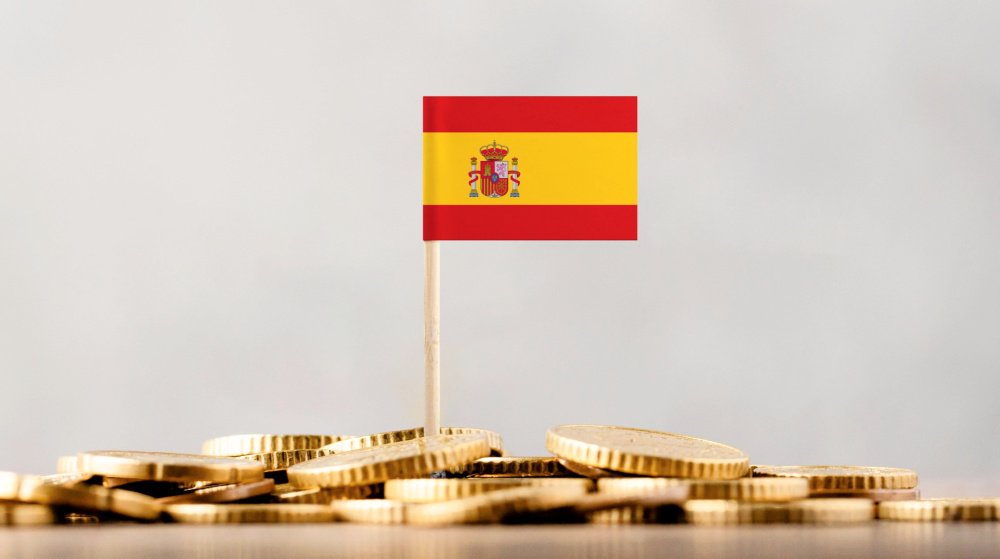 IBI tax Spain guide for foreign property owners — Spanish flag on gold coins representing annual property tax obligations